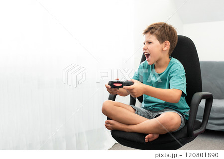 Boy plays a computer game with headphones and a joystick, game console. 120801890