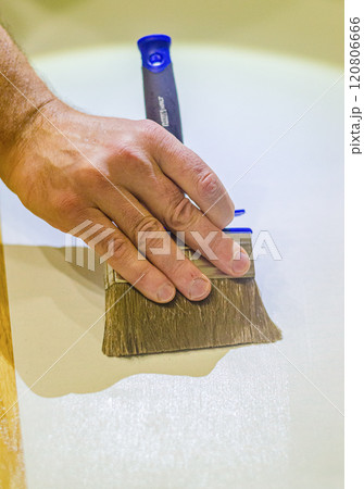 male hand applying colourless glue by brush for gluing wallpaper . High quality photo 120806666