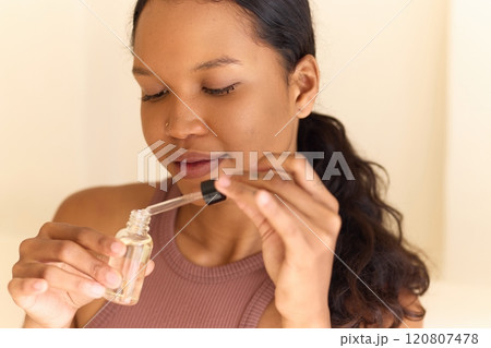 Woman Applying Face Serum for Glowing Skin in Natural Light Setting 120807478