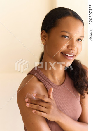 Woman Applying Moisturizer With Gentle Smile in Natural Light Setting 120807577