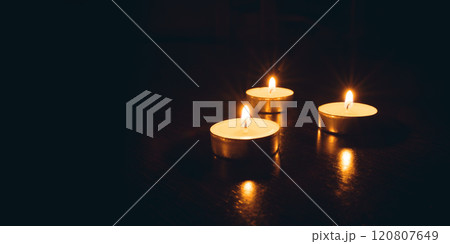 Three burning candles on a black background. Three burning candles on a black background. 120807649