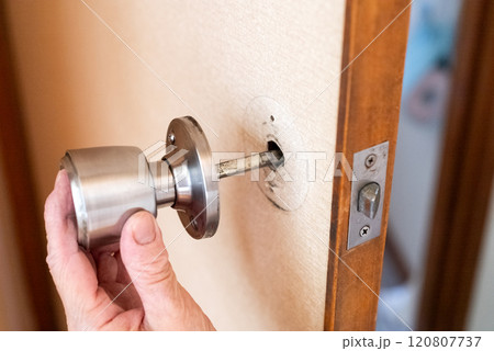 古い家のドアノブを直すシニア女性の手元 古い家のドアノブを直すシニア女性の手元 120807737