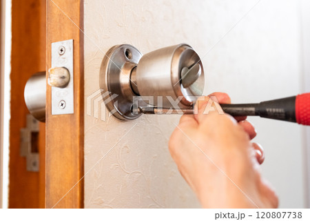 古い家のドアノブを直すシニア女性の手元 120807738