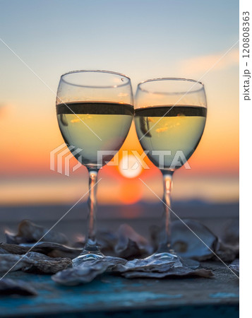 Two glasses of wine at sunset with oyster shells on table Two glasses of wine at sunset with oyster shells on table 120808363