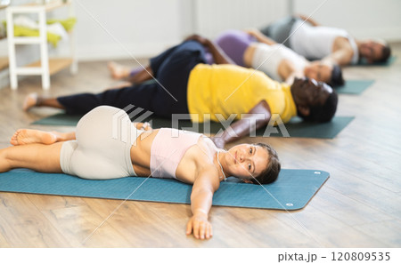 Girl performing Supta Matsyendrasana during group yoga session 120809535