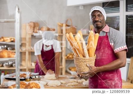 Successful African baker presenting golden baguettes in bakery Successful African baker presenting golden baguettes in bakery 120809539