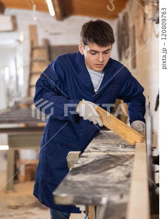 Young man cutting wooden board with circular saw at sawmill 120809763