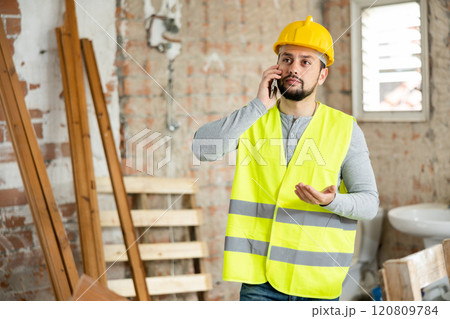 Builder is talking on a mobile phone Builder is talking on a mobile phone 120809784