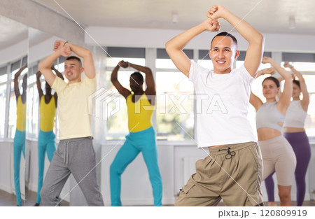 Group of young women and men in sportswear performing contemporary street dance in training room 120809919