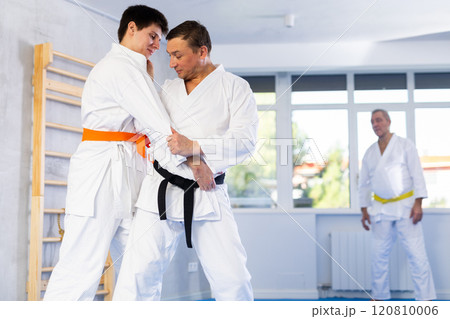 Jiu-jitsu master demonstrating basic grabs and throws in sparring with young fighter Jiu-jitsu master demonstrating basic grabs and throws in sparring with young fighter 120810006