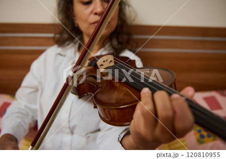 Close-up of woman playing a violin string instrument indoors 120810955