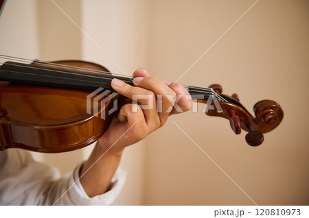 Close-up of a person playing a violin, showcasing skilled finger placement Close-up of a person playing a violin, showcasing skilled finger placement 120810973