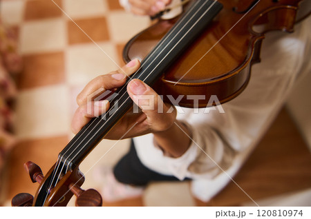 Close-up of a person playing violin in a warm indoor setting 120810974