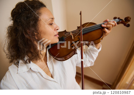 Woman playing a violin in a bright room with concentration Woman playing a violin in a bright room with concentration 120810987