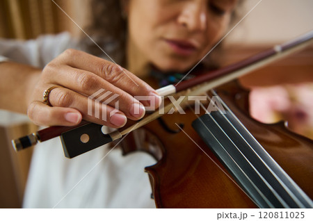 Close-up of woman playing violin with focused expression and gentle touch 120811025