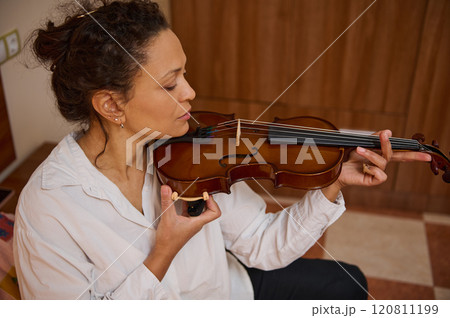 Woman playing the violin with focus and passion in a warm room 120811199