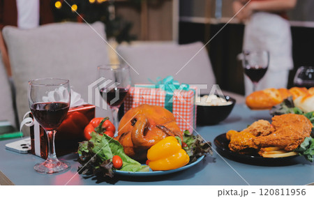 Group of young Asian man and women as friends having fun at a New Year's celebration, holding gift boxes standing by Christmas tree decoration, midnight countdown Party at home with holiday season. 120811956
