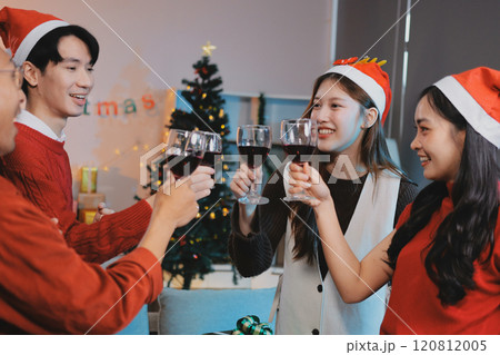 Group of young Asian man and women as friends having fun at a New Year's celebration, holding gift boxes standing by Christmas tree decoration, midnight countdown Party at home with holiday season. Group of young Asian man and women as friends having fun at a New Year's celebration, holding gift boxes standing by Christmas tree decoration, midnight countdown Party at home with holiday season. 120812005