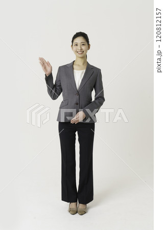 白背景のスーツを着た案内する若い女性の全身のポートレート　縦位置 120812157