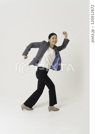 白背景のスーツを着てジャンプする若い女性の全身のポートレート　縦位置 120812672