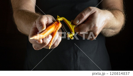 Bright orange carrots are held firmly as hands expertly peel their skin away, showcasing culinary skill in a warm, intimate kitchen setting filled with creativity and passion for cooking Bright orange carrots are held firmly as hands expertly peel their skin away, showcasing culinary skill in a warm, intimate kitchen setting filled with creativity and passion for cooking 120814837