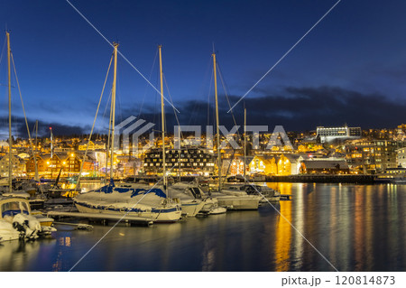 Panorama of the Norwegian city of Tromso on a winter evening during the Christmas season. The boat dock and downtown are illuminated by city lights. Panorama of the Norwegian city of Tromso on a winter evening during the Christmas season. The boat dock and downtown are illuminated by city lights. 120814873
