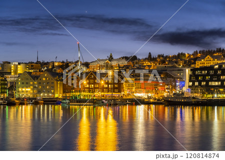 Panorama of the Norwegian city of Tromso on a winter evening during the Christmas season. The boat dock and downtown are illuminated by city lights. Panorama of the Norwegian city of Tromso on a winter evening during the Christmas season. The boat dock and downtown are illuminated by city lights. 120814874