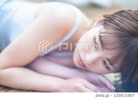 フローリングに寝転ぶショートボブの若い女性 120815807