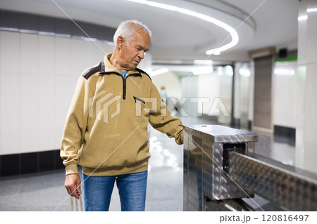 Elderly man at the turnstile in front of the entrance Elderly man at the turnstile in front of the entrance 120816497
