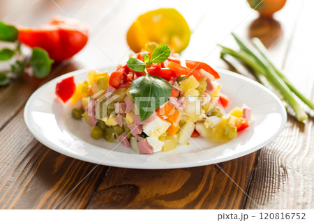 vegetable salad of boiled vegetables, with peas, sausage, sweet pepper. On a wooden table 120816752