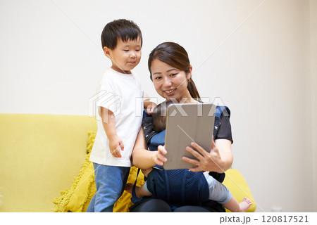 ソファに座ってタブレットPCの画面を見る親子 120817521