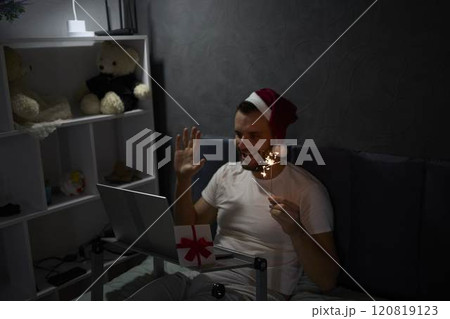 30-year-old man celebrates Christmas, New Year online with colleagues, friends at night with the light of a lamp 120819123