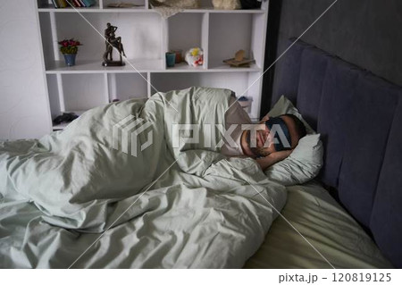 30-year-old man with a silk sleep mask is sleeping in bed 30-year-old man with a silk sleep mask is sleeping in bed 120819125