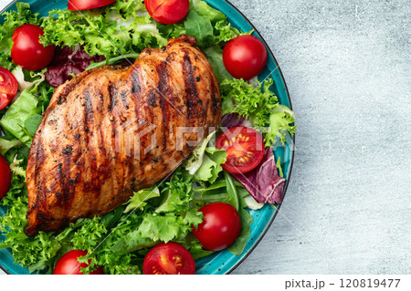 Grilled chicken breast ( fillet ) with lattuce salad and cherry tomatoes . Top view 120819477