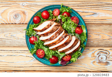 Grilled chicken breast ( fillet ) with lattuce salad and cherry tomatoes . Top view 120819483