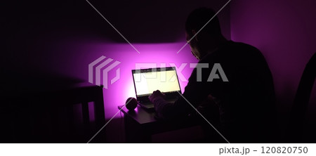 Young man silhouette sitting computer laptop in studio on violet background 120820750