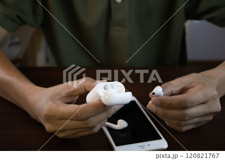 An Asian man is about to use wireless headphones that connect to his smartphone. An Asian man is about to use wireless headphones that connect to his smartphone. 120821767