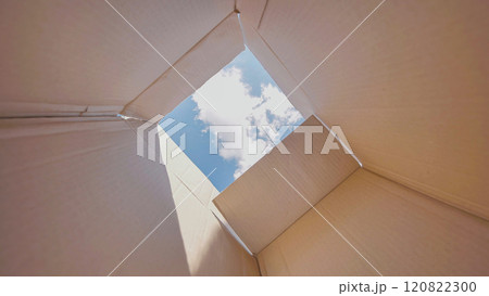 Open cardboard box is revealing a blue sky with some clouds, suggesting freedom, hope and new possibilities 120822300