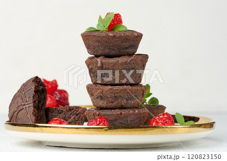 Chocolate brownies stacked with the top adorned by a red juicy cherry and mint leaves 120823150