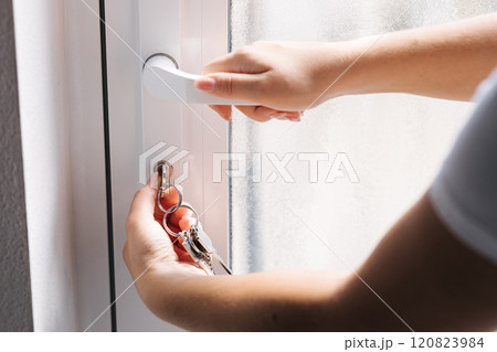 First person woman's hand holding keys and unlocking a door with a metal handle. 120823984