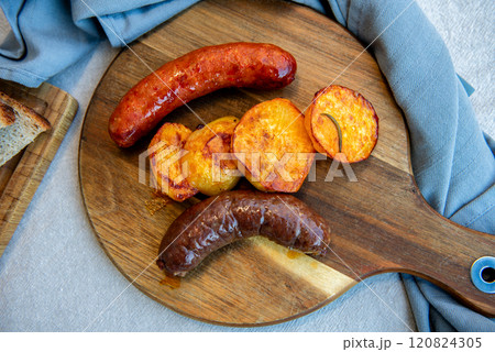 Close-up of homemade sausages on wooden cutting board with potatoes. homemade traditional food 120824305