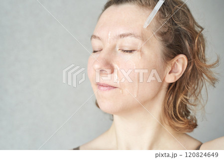 Adult caucasian female applying skincare serum with dropper for facial 120824649
