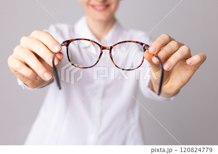 ophthalmologist doctor putting glasses on patient, pulling glasses forward, vision concept 120824779