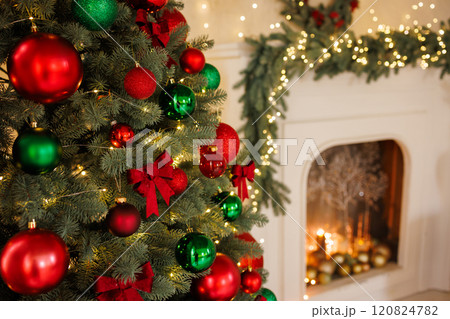 Christmas red bow on a tree, close-up, against the background of a fireplace, stylish New Year's decor 120824782