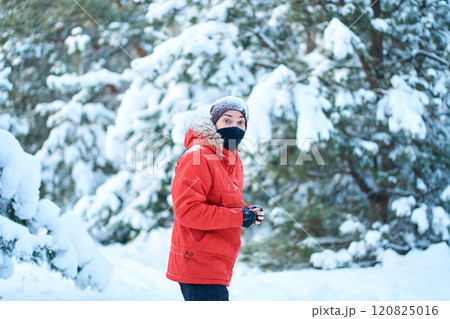 Guy in red winter jacket walk though snow covered winter forest Guy in red winter jacket walk though snow covered winter forest 120825016
