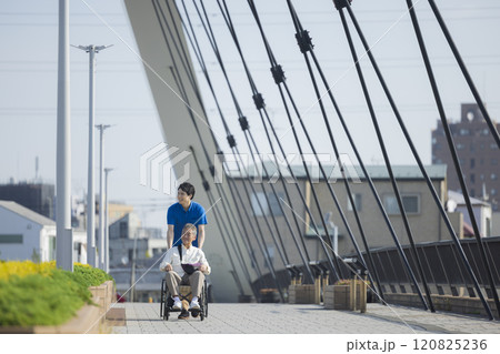 屋外で車椅子を押す介護スタッフ 120825236