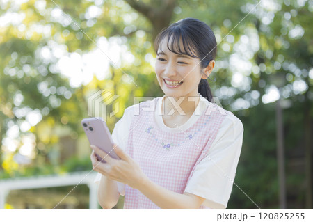 スマホを持った保育士の若い女性 スマホを持った保育士の若い女性 120825255