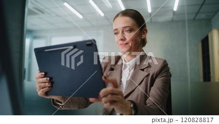 Businesswoman chatting with business partner via video call using tablet computer 120828817