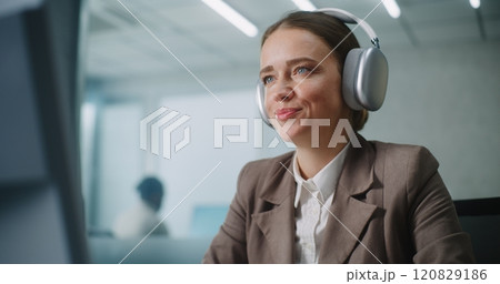 Businesswoman wearing headphones works on computer, chats with business partner Businesswoman wearing headphones works on computer, chats with business partner 120829186