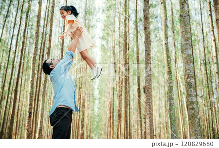 Playful family moment, father holds happy little girl up high, throwing up in sky at park forest. cheerful child enjoy moment playing freedom and joy, while loving dad captures precious memory forever 120829680